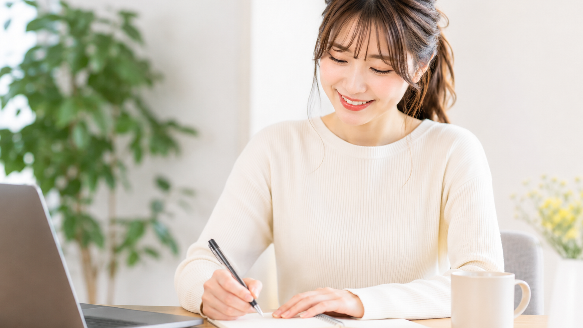 ノートに手書きでアイデアを書き出しながら微笑む22歳の日本人女性